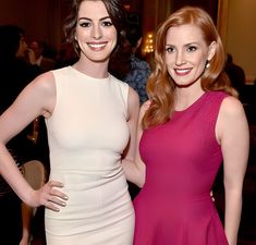 two beautiful women standing next to each other in front of a room full of people