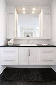 a bathroom with white cabinets and black counter tops