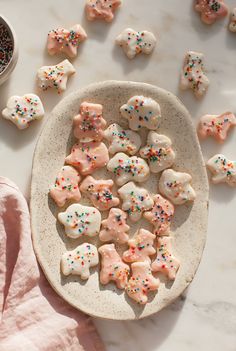 a plate full of sugar cookies with sprinkles on it next to a bowl of sprinkles