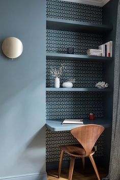 a blue room with a chair and shelves on the wall next to a book shelf