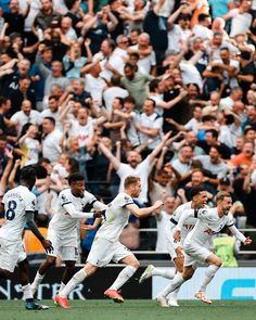 the soccer players are celebrating their team's goal in front of a large crowd