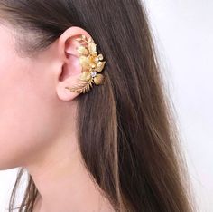 Gorgeous modern style ear cuff decorated with delicately shaped leaves. You can use our ear cuff on the right or left side. Has a rode metal soldered on the back of it that could be opened for an easy wear or squeezed inwards for a secure fit. The set includes a mini zirconium stud earring for the second ear Length: 2.5 Inches; Width: 1 Inches VAT: Value Added Tax (VAT) is a tax that is charged when your parcel reaches the destination country. You may be required to pay VAT in order to receive y Gold Single Earring Ear Cuff For Wedding, Gold Solitaire Ear Cuff For Wedding, Elegant Gold Ear Climbers For Wedding, Dainty Gold Ear Cuff For Wedding, Elegant Wedding Ear Climbers, Gold Clip-on Ear Cuff For Wedding, Dainty Silver Ear Cuff For Wedding, Dainty Single Cartilage Earring For Wedding, Elegant Pierced Wrap Earrings For Wedding