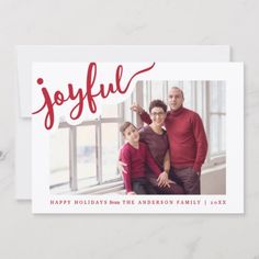 the joyful holiday card features an image of two adults and a child in front of a window