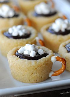 mini desserts with marshmallows and pretzels in them on a white plate