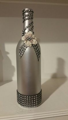 a silver bottle with flowers on it sitting on a shelf