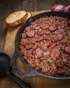 a skillet filled with sausage and beans next to bread