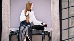 a woman with long hair sitting on a bench next to a black and white cat