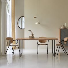 two chairs and a table in a room with white walls, one has a round mirror on the wall