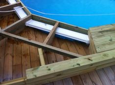 a wooden deck next to a pool with a bench on the bottom and an above ground swimming pool in the middle