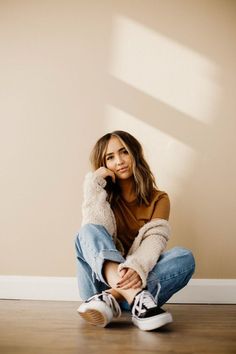 a woman sitting on the floor with her hand under her chin