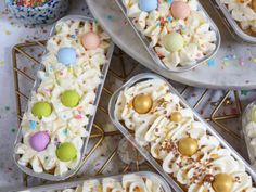 an assortment of desserts in plastic containers with sprinkles and eggs on them