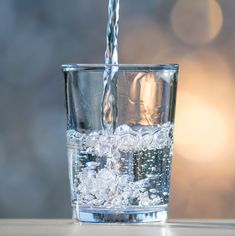 water being poured into a glass filled with ice