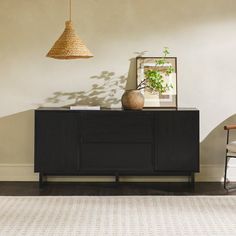 a living room with a rug, table and lamp on it's sideboard