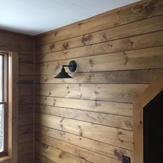 an empty room with wood paneling and a light fixture on the wall next to a window