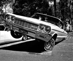 an old car is parked on the side of the road next to a white car