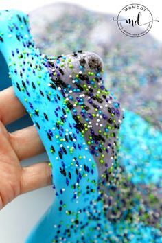 a hand holding a blue ring with green and purple sprinkles