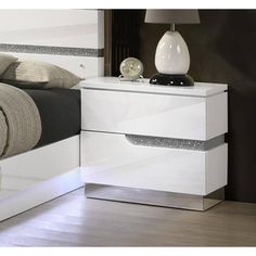 a white night stand with two drawers and a lamp on the nightstand next to it