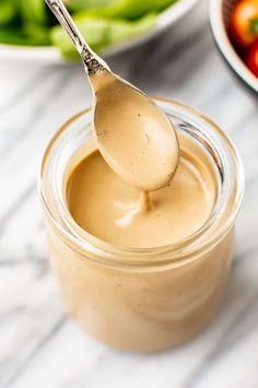 a spoon full of peanut butter next to some vegetables