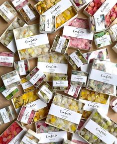 many different types of candies in small boxes on a table with name tags attached to them