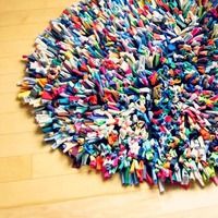 a round rug made out of crayons is on the floor next to a trash can