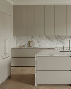 a large kitchen with marble counter tops and white cupboards on the wall, along with wooden flooring