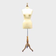 a mannequin is standing on a wooden tripod and has a white top