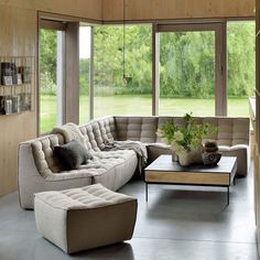 a living room filled with lots of furniture next to large windows and wooden paneled walls