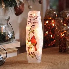 a lighted christmas vase sitting on top of a table next to other ornaments and decorations