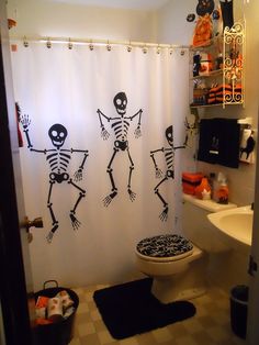 a bathroom decorated in halloween theme with skeletons on the shower curtain