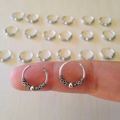 small silver hoop earrings sitting on top of a person's finger