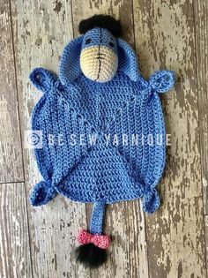 a crocheted blue monkey hat and diaper cover laying on the floor with a black pom - pom