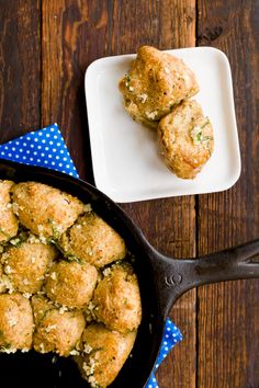 some food that is in a pan on a wooden table next to a blue and white napkin