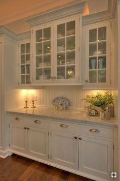 a kitchen with white cabinets and wooden floors