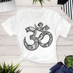 a t - shirt with an om symbol on it next to a laptop and plant