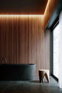 a black bath tub sitting next to a wooden wall