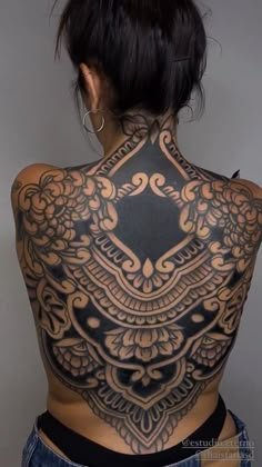 the back of a woman's body with intricate tattoos on her upper and lower back