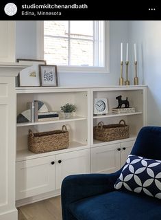 a blue chair sitting in front of a white book shelf filled with books and baskets