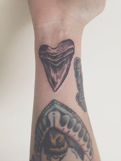 a person's arm with tattoos on it, including a heart and other items