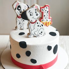 a white cake with black and red polka dots has two small dogs on top of it