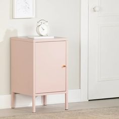 a small pink cabinet next to a white door with a clock on it's top