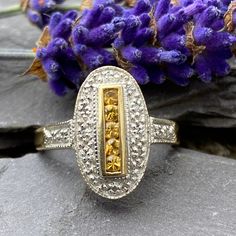 An Art Deco style ring in 9ct gold set with five round brilliant yellow sapphires surrounded by a deep Rhodium border set with eleven Round brilliant Diamond accents and two further Diamonds to the shoulders. Ornate pierced gallery. 9ct yellow gold shank. 375 Birmingham In excellent condition Will arrive gift boxed Free tracked shipping/UK next day delivery. Art Deco Gold Rings With Halo Setting, Gold Art Deco Ring With Halo Setting, Gold Art Deco Rings With Halo Setting, Gold Oval Sapphire Ring In Art Deco Style, Art Deco Gold Cluster Ring With Rose Cut Diamonds, Hallmarked Yellow Diamond Ring, Classic Yellow Hallmarked Rings, Art Deco Yellow Gold Birthstone Rings, Art Deco Sapphire Ring In Yellow Gold