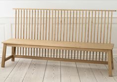 a wooden bench sitting on top of a hard wood floor next to a white wall