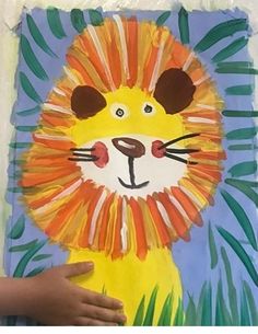 a child's hand holding up a paper lion