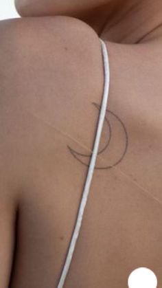 the back of a woman's shoulder with a circle tattoo on her left arm