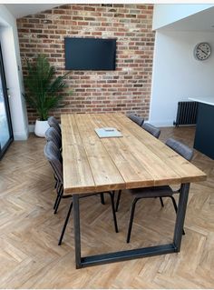 a wooden table sitting inside of a room next to a tv mounted on a brick wall