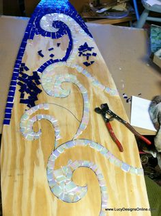 a surfboard is being worked on with some glass and wood pieces in the shape of numbers