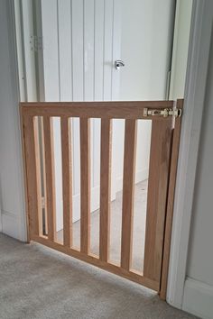 an open wooden gate in the corner of a room with carpeted floor and white walls