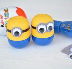 two yellow and blue minion toys sitting on top of a table next to a hammer