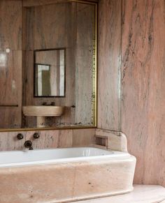 a bath tub sitting under a mirror in a bathroom