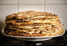 a stack of pancakes sitting on top of a white plate over an oven burner